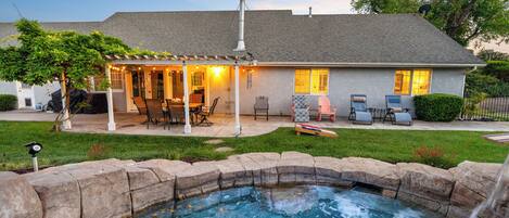 A house with a backyard patio, a hot tub, and a covered outdoor seating area.