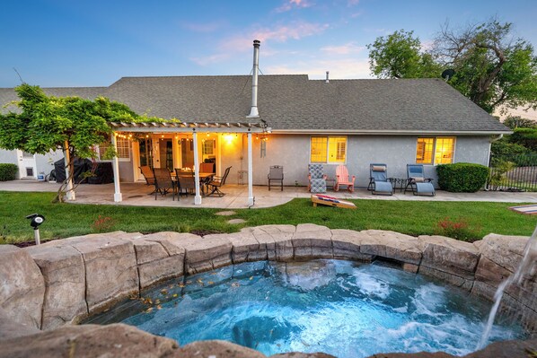 A house with a backyard patio, a hot tub, and a covered outdoor seating area.