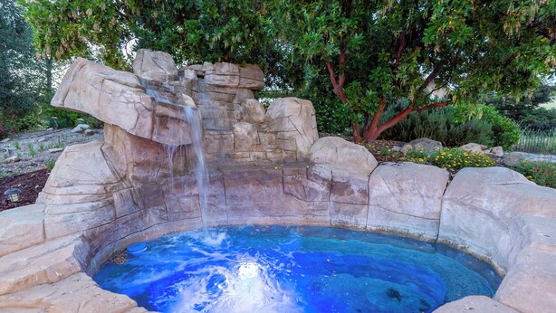 A hot tub surrounded by a rock formation with a waterfall feature. - Waterfall Spa + Sunset Views | Atascadero Wine Country | Summer Place (Templeton)