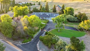 A residential property with a large house, solar panels, and a well-maintained lawn. - Waterfall Spa + Sunset Views | Atascadero Wine Country | Summer Place (Templeton)