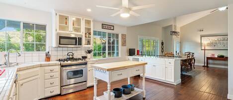 A modern kitchen with white cabinetry, a central island, and a ceiling fan.