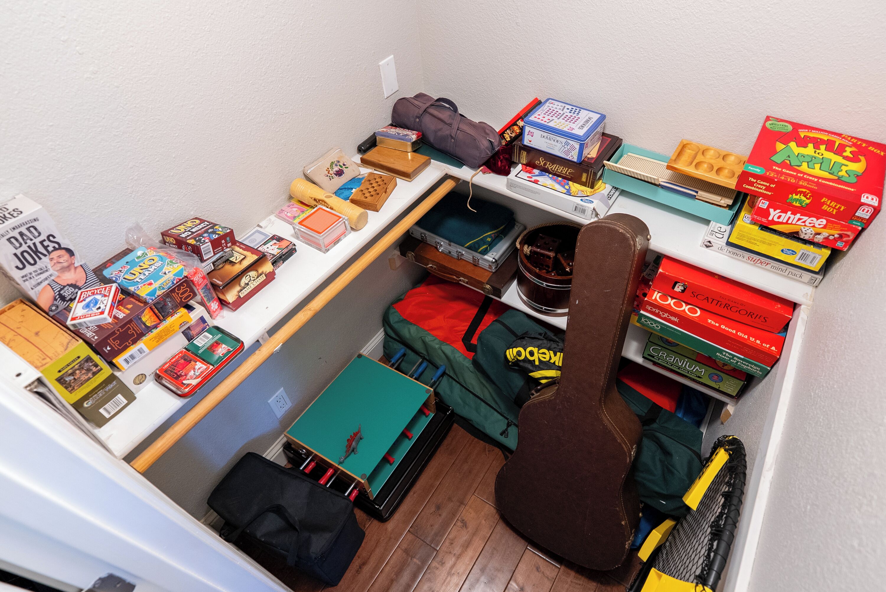 A compact room with a variety of board games, a guitar, and a suitcase.