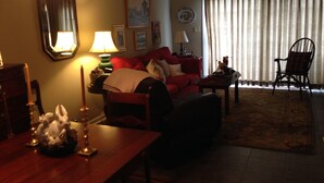 Ein Wohnzimmer mit einem roten Sofa, einem Holztisch und einem Esstisch mit Kerzen als Mittelstück.