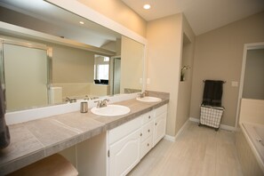Une salle de bain avec deux lavabos, un grand miroir, un porte-serviettes et une baignoire.