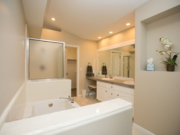 A modern bathroom with a bathtub, a large mirror, and a vanity with a sink.