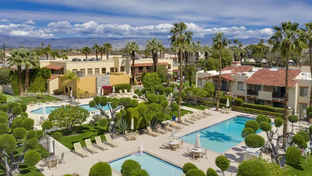 Ein Resort mit mehreren Schwimmbecken, Palmen und einer Bergkulisse.