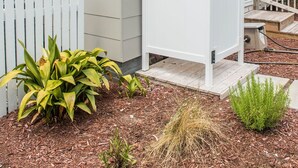 Ein Haus mit weißem Zaun, Garage und einem kleinen Garten mit Pflanzen.