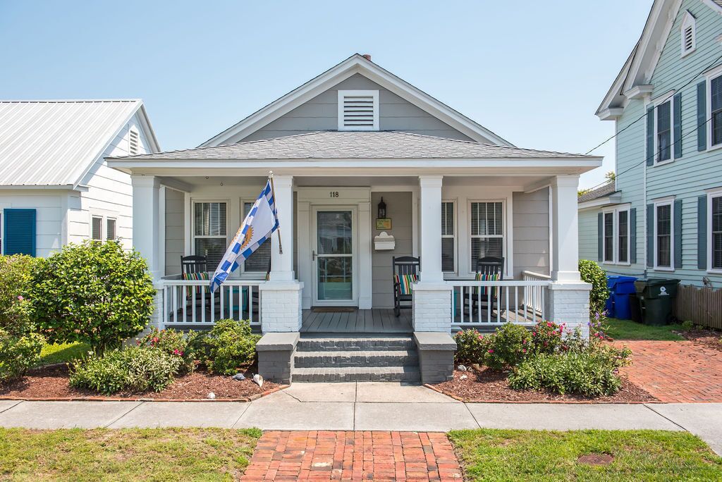 Une maison à deux étages avec un porche à l’avant, un drapeau et une boîte aux lettres.