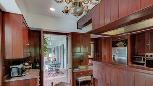 A spacious kitchen with wooden cabinets, a dining area with a table and chairs, and a refrigerator. - Bayou Liberty Waterfront Estate (Slidell)