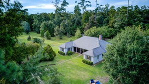 A house with a large lawn, a covered patio, and a garage. - Bayou Liberty Waterfront Estate (Slidell)