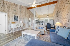 A spacious living area with a sofa set, a coffee table, and a dining table with chairs. - Renovated Sea Dunes 2BR with Ocean Views Private Deck and Pool Next Door (New Smyrna Beach)