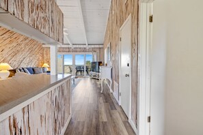 Ein Flur mit einer Holzwand, einer weißen Tür und Blick ins Freie.