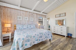 Een slaapkamer met een bed, een dressoir, een nachtkastje en een muur met ingelijste foto's.