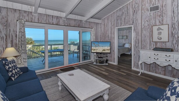 A living room with a view of the ocean, a sofa, a coffee table, and a TV. - Sunnyside Up Townhome at Sea Dunes - Ocean View & Next to Pool - B6 Up (New Smyrna Beach)