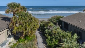 A coastal residential area with a view of the ocean, a wooden pathway, and houses with a beach in the background. - Sunnyside Up Townhome at Sea Dunes - Ocean View & Next to Pool - B6 Up (New Smyrna Beach)