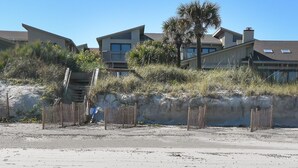 A beachfront property with multiple-story buildings, a palm tree, and a sandy beach. - Sunnyside Up Townhome at Sea Dunes - Ocean View & Next to Pool - B6 Up (New Smyrna Beach)