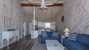 A living room with a blue sofa, a white coffee table, and a ceiling fan. - Sunnyside Up Townhome at Sea Dunes - Ocean View & Next to Pool - B6 Up (New Smyrna Beach)