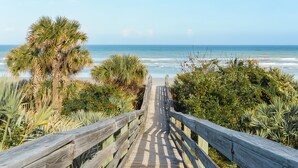 A wooden boardwalk leading to a beach with palm trees and ocean views. - Getaway New Smyrna Beach, Sun, Pool, Shopping. (New Smyrna Beach)