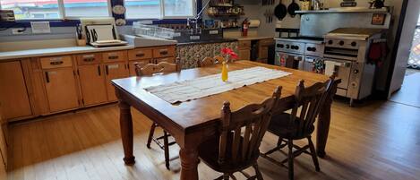 Una cocina con armarios de madera, una mesa de comedor con sillas, un jarrón con flores y una estufa.