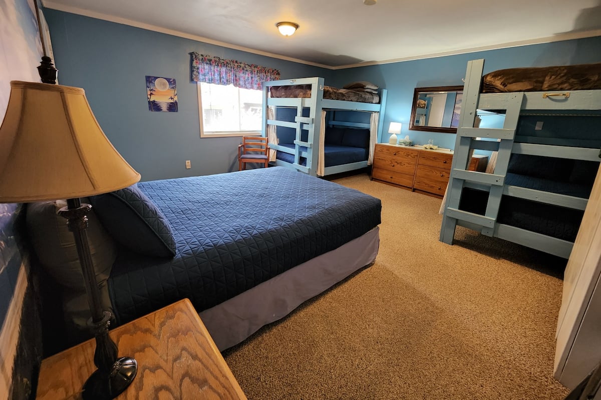 A bedroom with bunk beds, a desk, and a lamp.