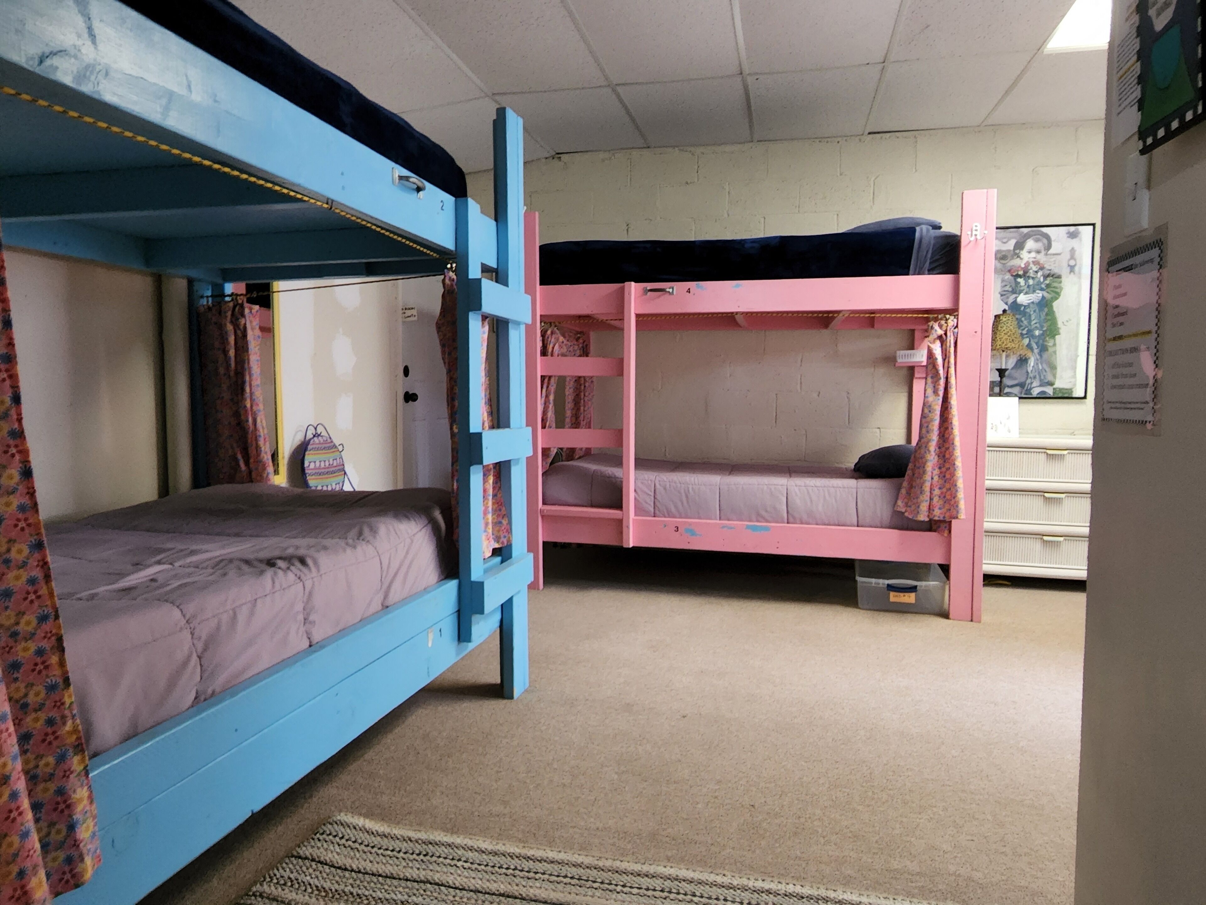 A bunk bed room with a blue bunk on the left and a pink bunk on the right.