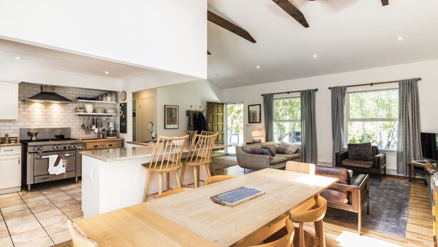 Amplia sala de estar con una mesa de comedor de madera, un sofá y una cocina con electrodomésticos modernos.