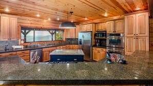 Un'ampia cucina con mobili in legno, piani di lavoro in granito ed elettrodomestici in acciaio inossidabile, con un'isola grande.