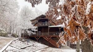 Una baita di legno con un balcone, circondata da alberi innevati.