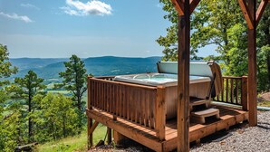 Una terrazza in legno con vasca idromassaggio e vista su un paesaggio montuoso.