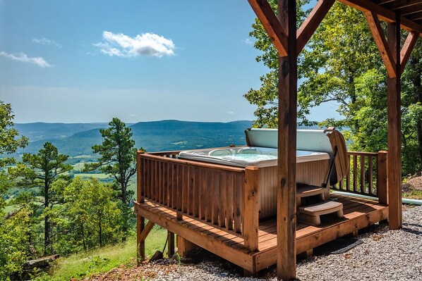 A wooden deck with a hot tub overlooking a mountainous landscape.