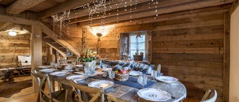 A wooden dining table set with plates, glasses, and a centerpiece.