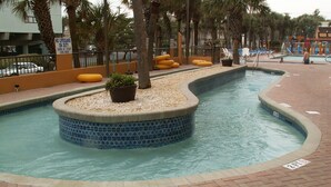 Ein Swimmingpool mit Fliesenrand, umgeben von einem Ziegelweg und Palmen.