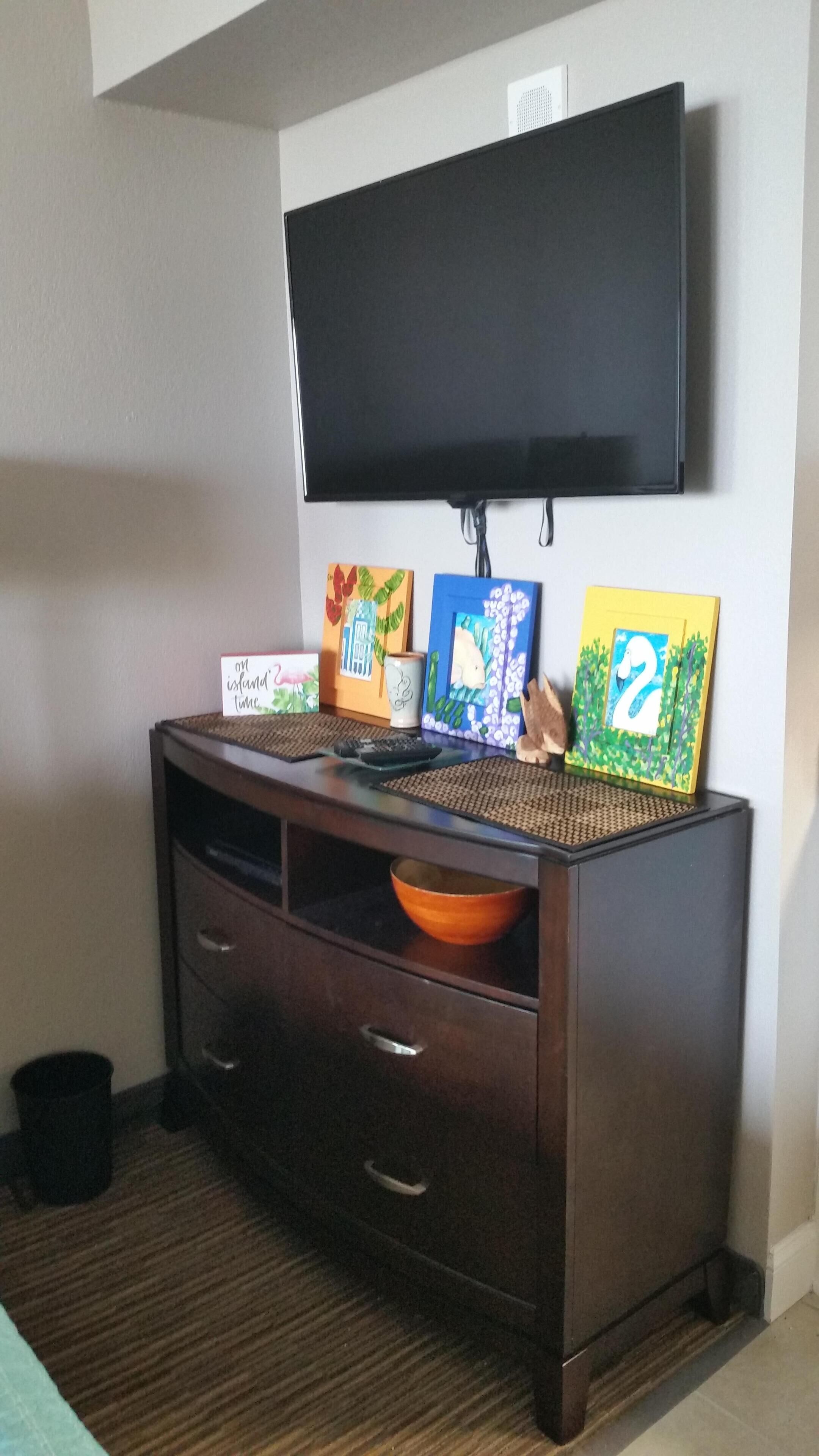 A dark wooden entertainment center with a flat-screen TV mounted above it.