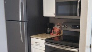 Eine Küche mit Edelstahl-Kühlschrank, Mikrowelle, Backofen und Geschirrspüler.