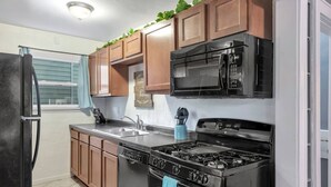 A kitchen with a refrigerator, stove, microwave, and wooden cabinets. - Welcome Home (+ your pup) MSU 2 mi (Lansing)