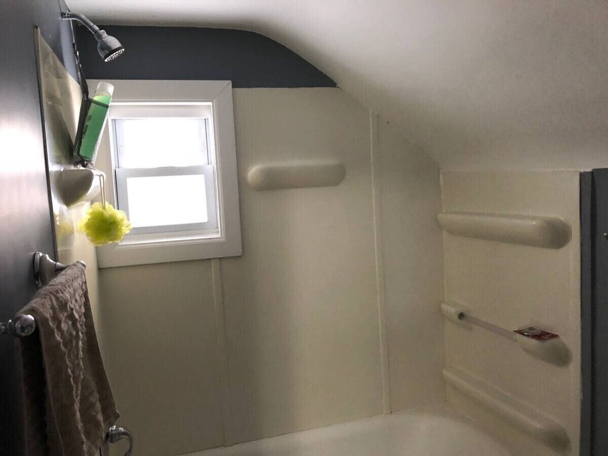 Un baño con bañera, ventana y perchero.