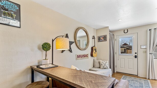 Un salon chaleureux avec une table basse en bois, une guitare, une lampe et un panneau indiquant « MUSIQUE ».