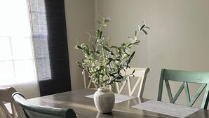 A dining room with a wooden table, six chairs, a vase with green plants, and a window with blinds. - Clean and open 3bd/2ba in a quiet close-in neighborhood (Tallahassee)