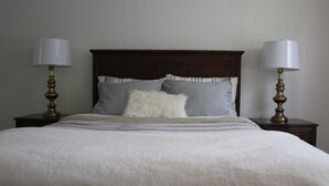 A neatly made bed with a white comforter and two pillows, flanked by two bedside tables with lamps. - Clean and open 3bd/2ba in a quiet close-in neighborhood (Tallahassee)