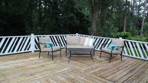 A wooden deck with a white railing, a beige sofa with teal cushions, and a small table. - Clean and open 3bd/2ba in a quiet close-in neighborhood (Tallahassee)