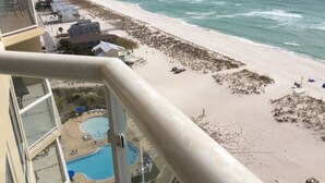 Vista a la playa desde un balcón con piscina y casas de playa.