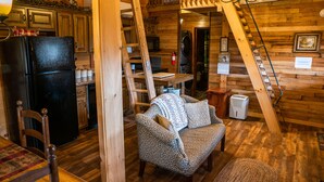 A cozy cabin interior with a wooden interior, a dining area with a table and chairs, a sofa, and a staircase. - NEW! Custom Cabin on 10 acres! (Sevierville)