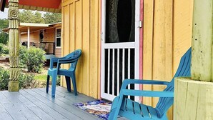 A wooden porch with two blue chairs and a red awning.