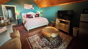 A cozy bedroom with a bed, a television, a dresser, and a wicker chair.