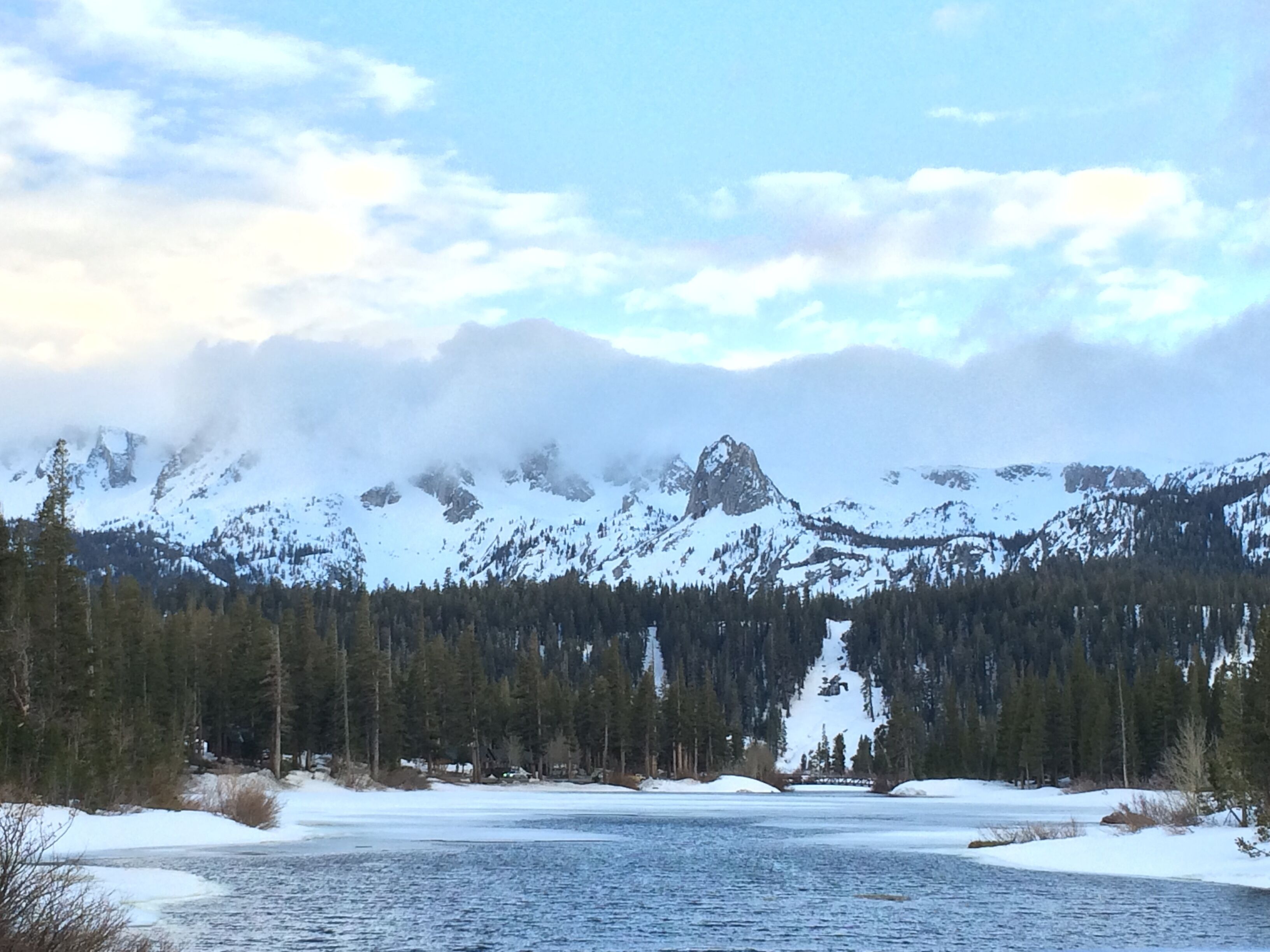 A lake surrounded by snow-covered mountains and dense forests.