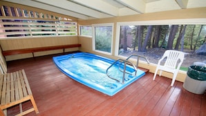 En indendørs swimmingpool med træterrasse, en bænk og en stol.