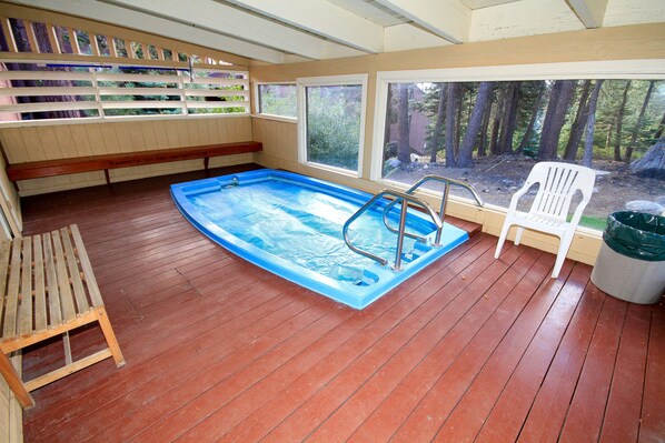 A rectangular pool with a ladder, wooden deck, and a bench.