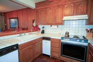 A kitchen with wooden cabinets, a dishwasher, an oven, and a stove.