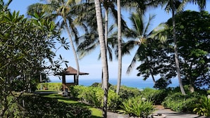 Un jardin tropical agrémenté d’un kiosque, de palmiers et offrant une vue sur l’océan.