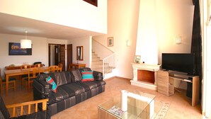 Una sala de estar con un sofá, una mesa de centro de vidrio, un televisor y una chimenea.